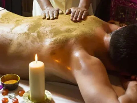 A person receiving a massage with a candle and a cup filled with oil 