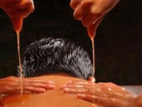 Person receiving a back massage with oil being applied.