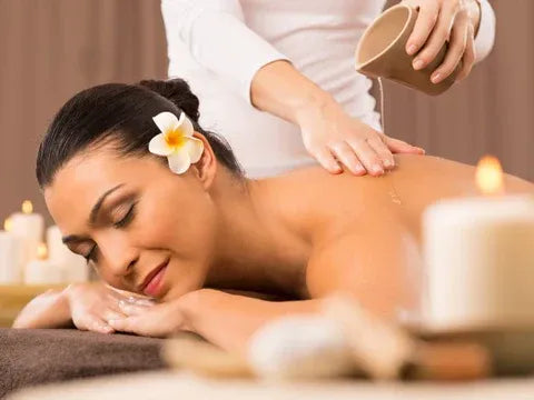 Woman receiving a massage with candles and a flower in her hair.